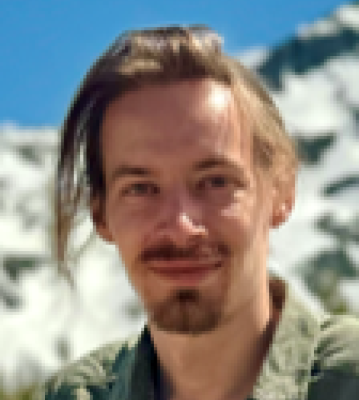Smiling young man with goatee and swept hair, photo against snowy mountain and blue sky