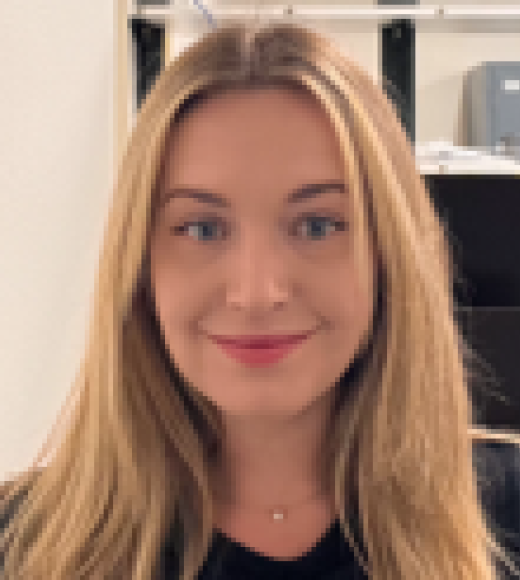 Close-up portrait of smiling woman with long blonde hair in front of office shelves