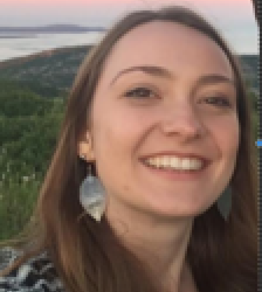 Smiling young woman outdoors at sunset with hills and a bay behind
