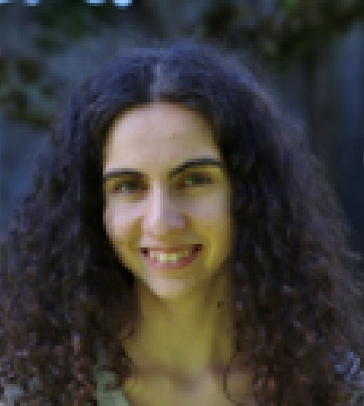 Smiling woman with curly dark hair outdoors, close-up portrait photograph