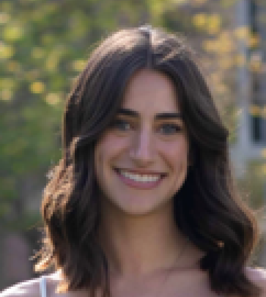 Smiling young woman with dark wavy hair, outdoor headshot photo, blurred green background
