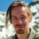 Smiling young man with goatee and swept hair, photo against snowy mountain and blue sky