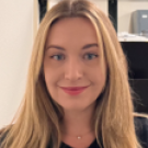Close-up portrait of smiling woman with long blonde hair in front of office shelves