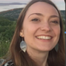 Smiling young woman outdoors at sunset with hills and a bay behind